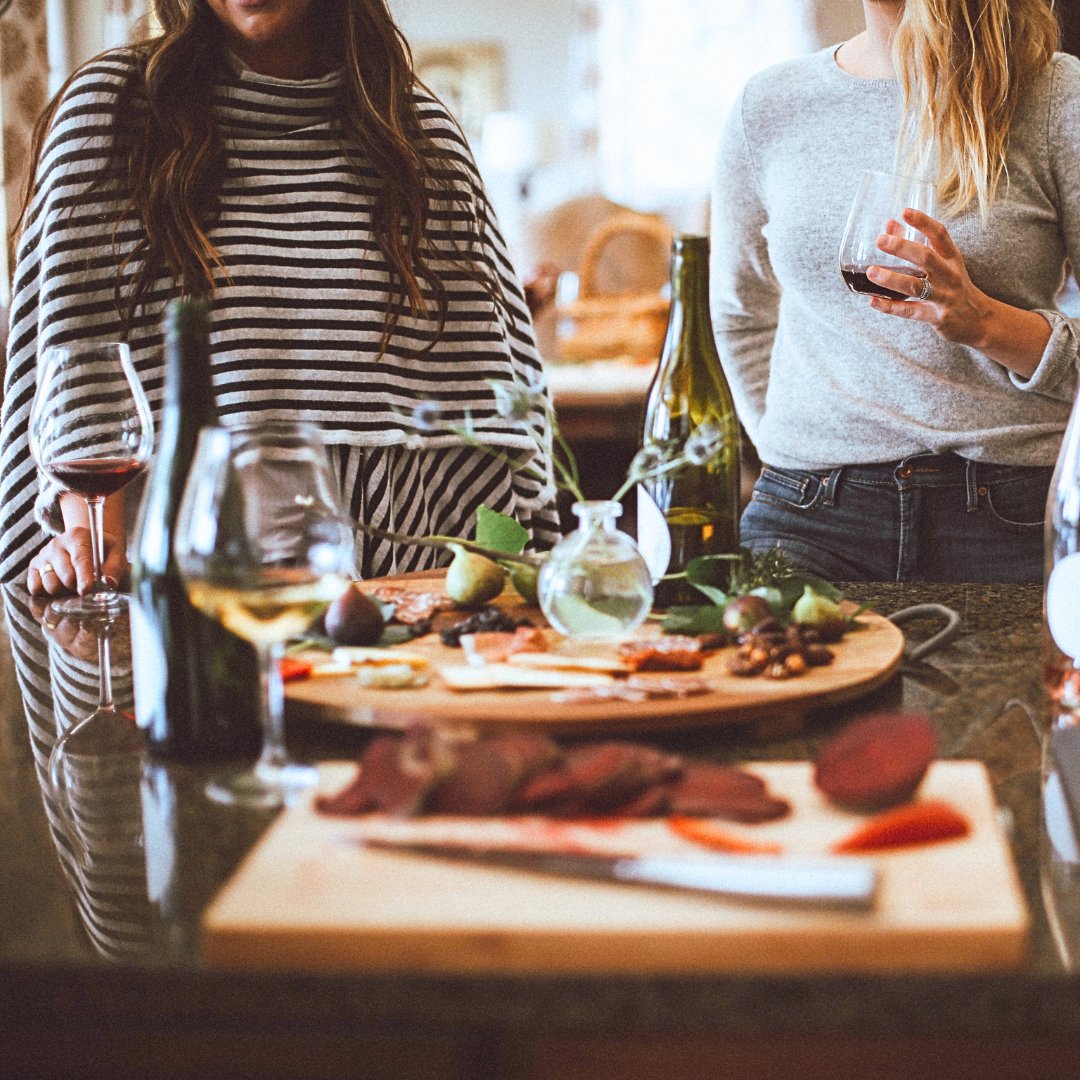 Friends sharing wine over a board at the kitchen counter